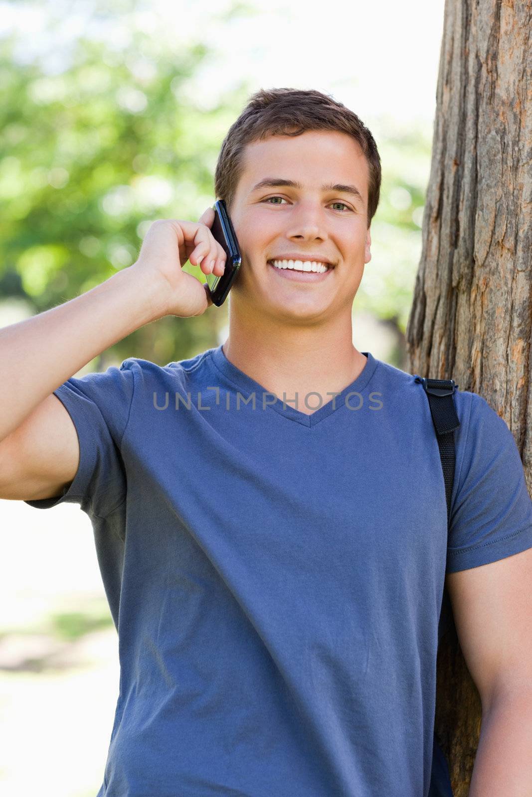 Portrait of a muscled young man on the phone in a park