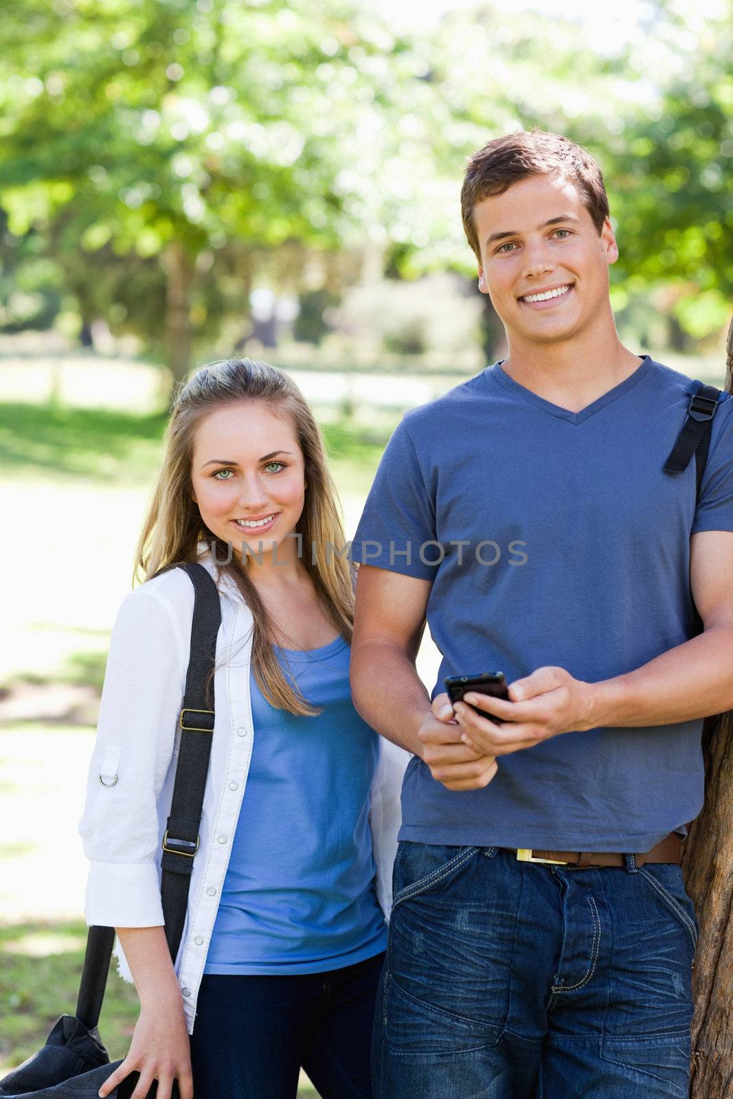 Portrait of two students with a smartphone in a park