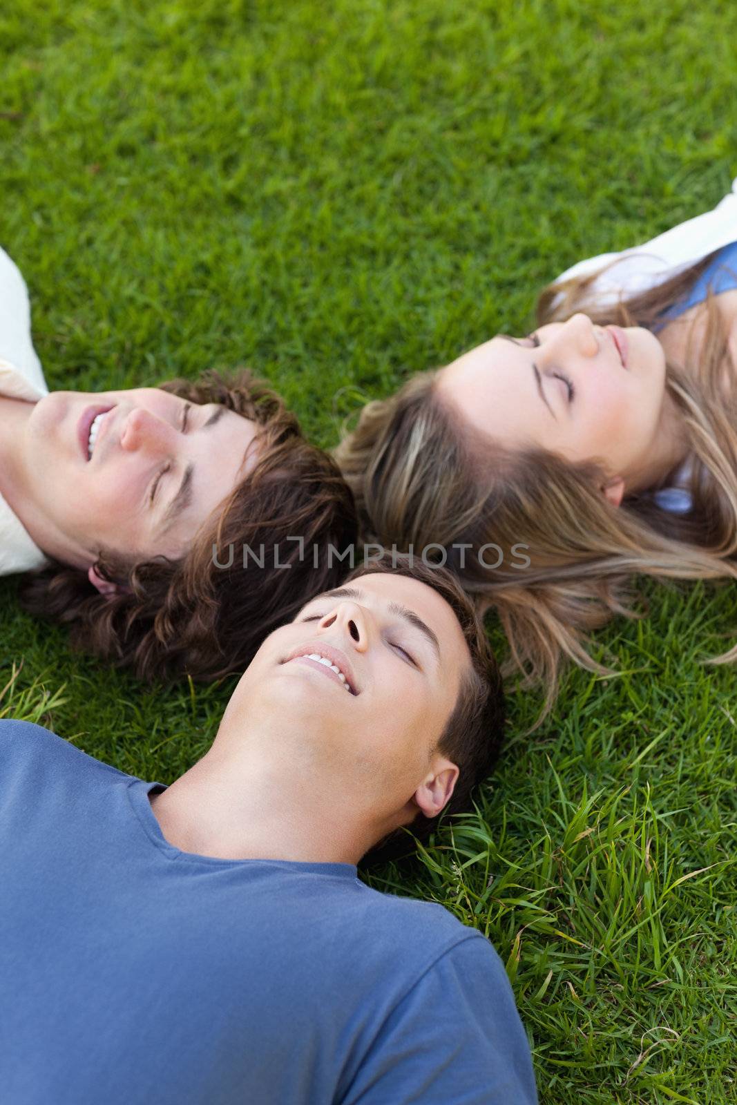 Three students lying together in the grass