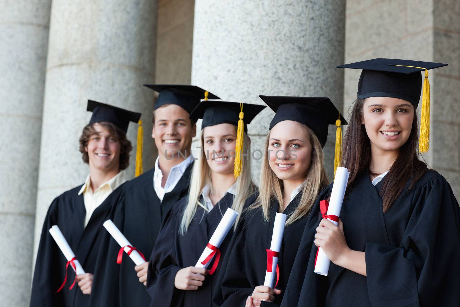 Graduates posing in single line with columns in background