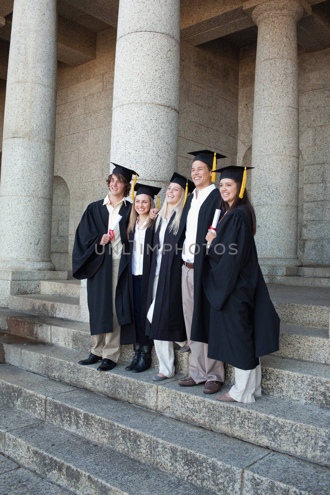 Graduates posing while smiling in front of the university