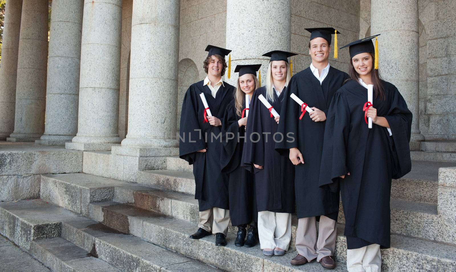 Five happy graduates posing by Wavebreakmedia