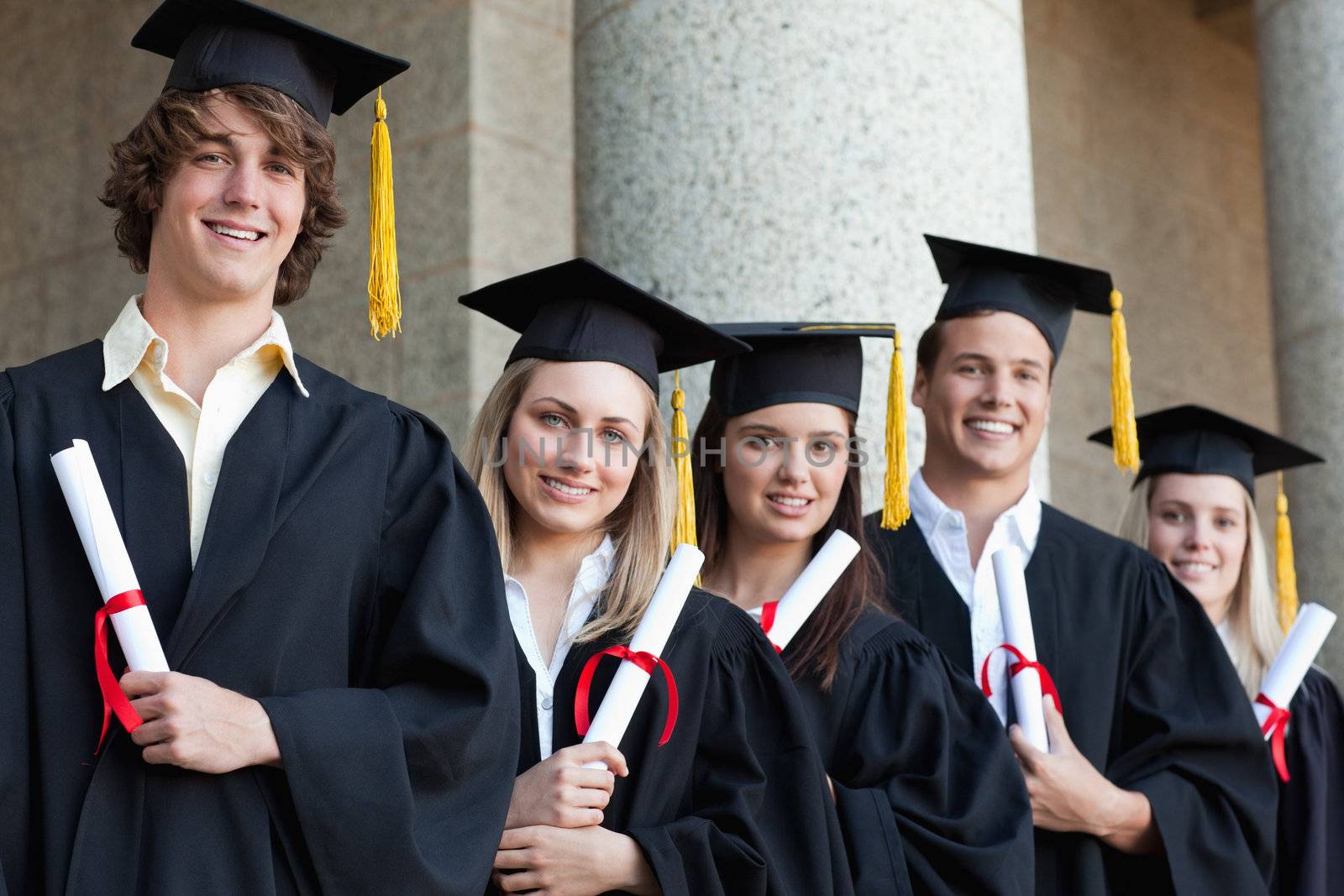 Close-up of five graduates students posing in front of the university
