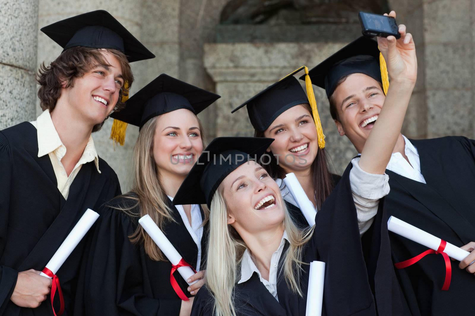 Close-up of happy graduates taking a picture of themselves in front of the university