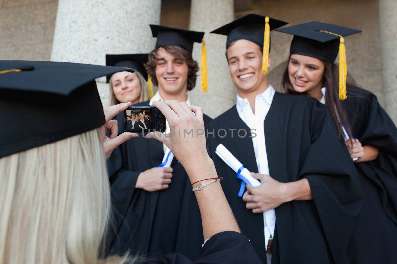 Close-up of a female graduate taking a picture of her friend in front of the university