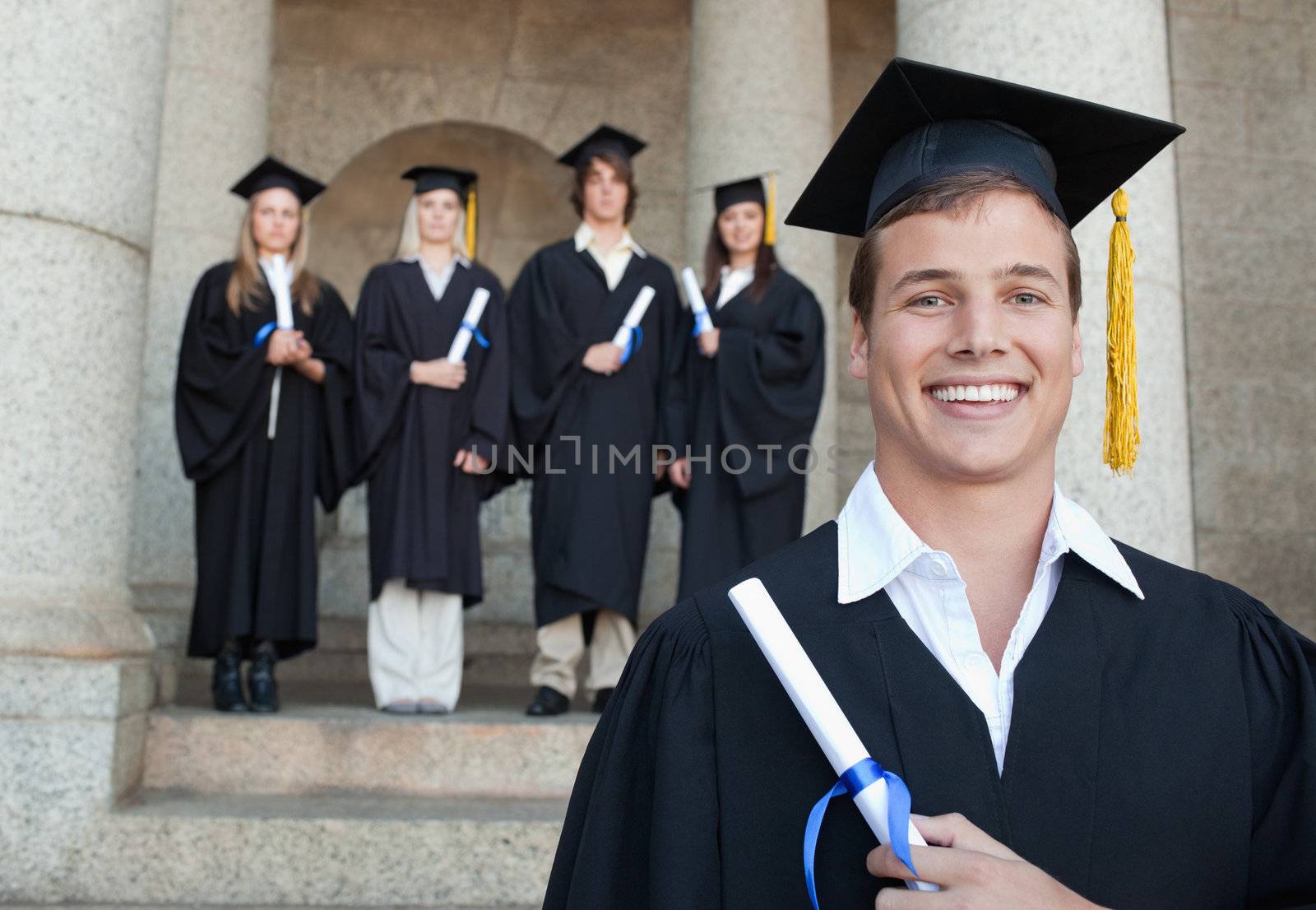 Close-up of a happy graduate smiling with her friends in background in front of the university