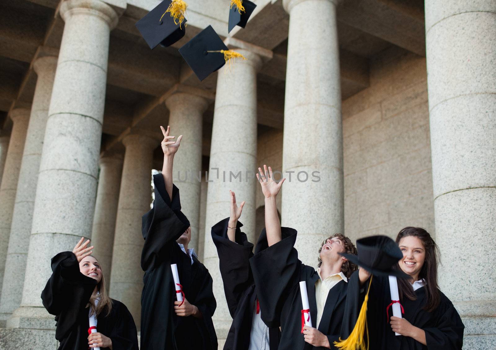 Happy graduates throwing their hats in the sky  by Wavebreakmedia