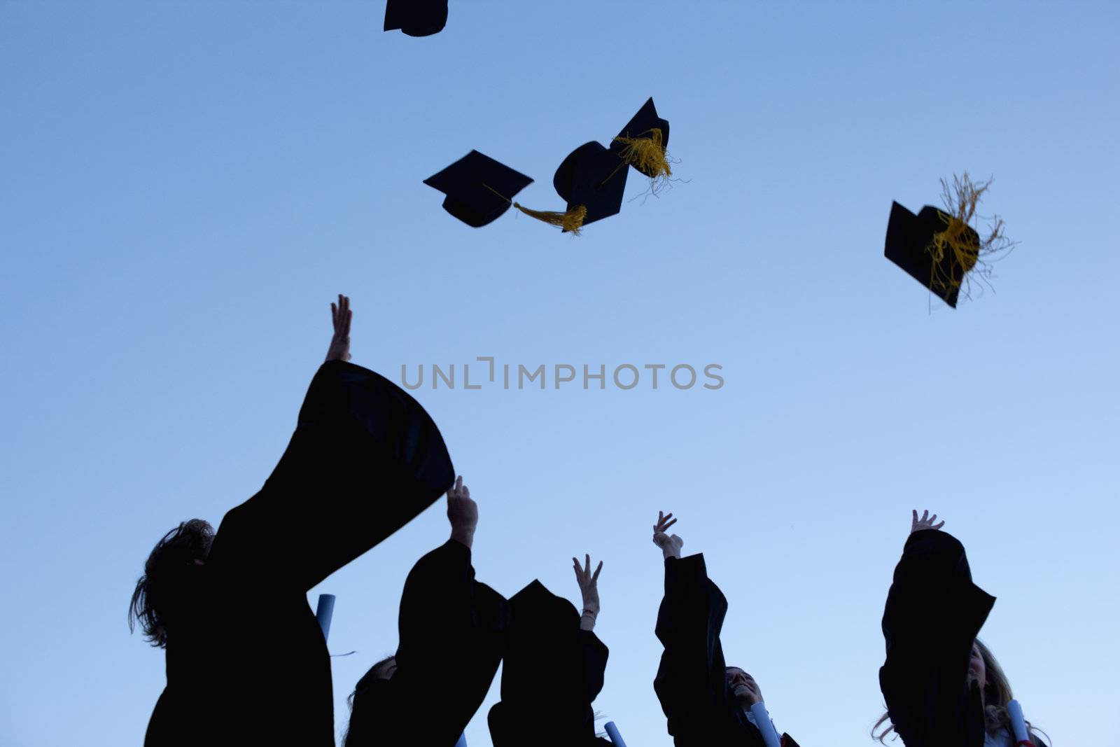 Five graduates throwing their hats in the sky  by Wavebreakmedia