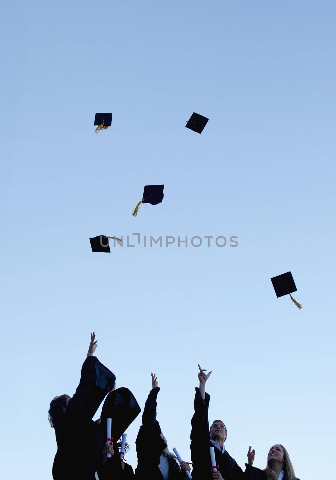 Five grad students throwing their hats high in the sky  by Wavebreakmedia