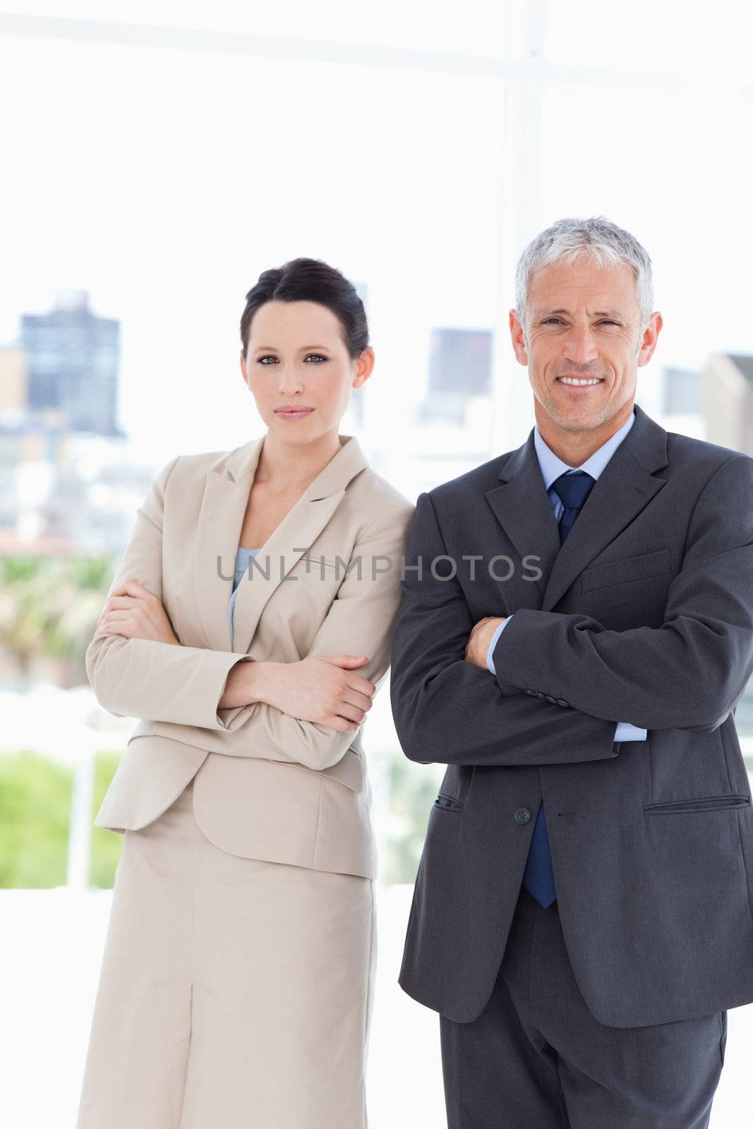 Young secretary standing upright next to her serious and mature director