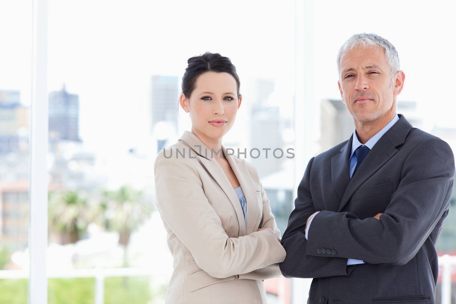 A young secretary and her director proudly crossing their arms