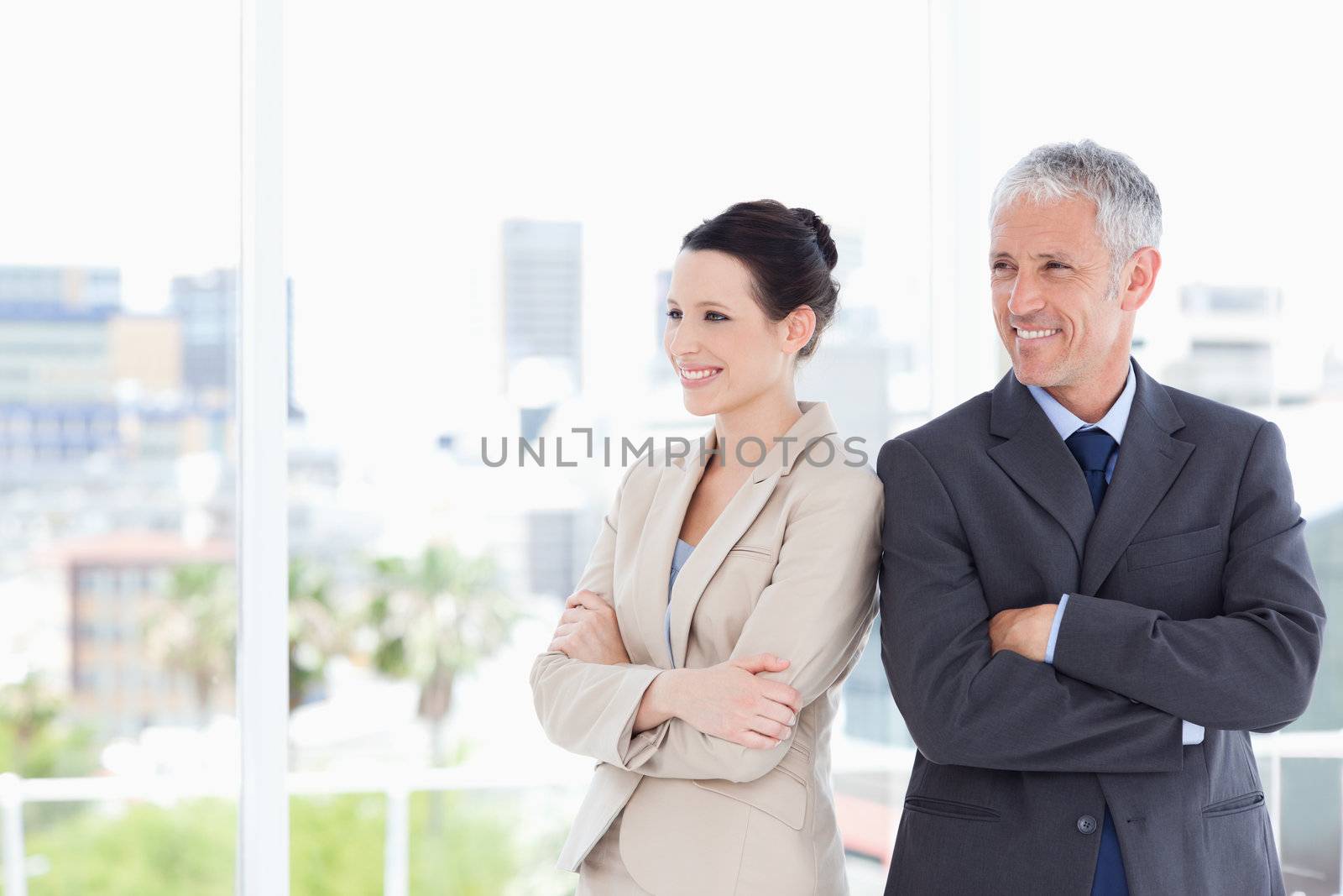 Business people crossing their arms while looking towards the side and smiling