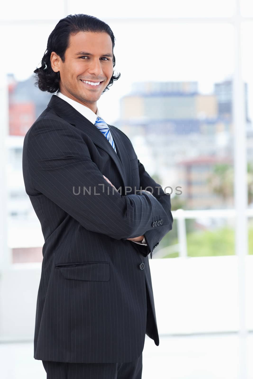 Smiling executive crossing his arms while looking at the camera by Wavebreakmedia