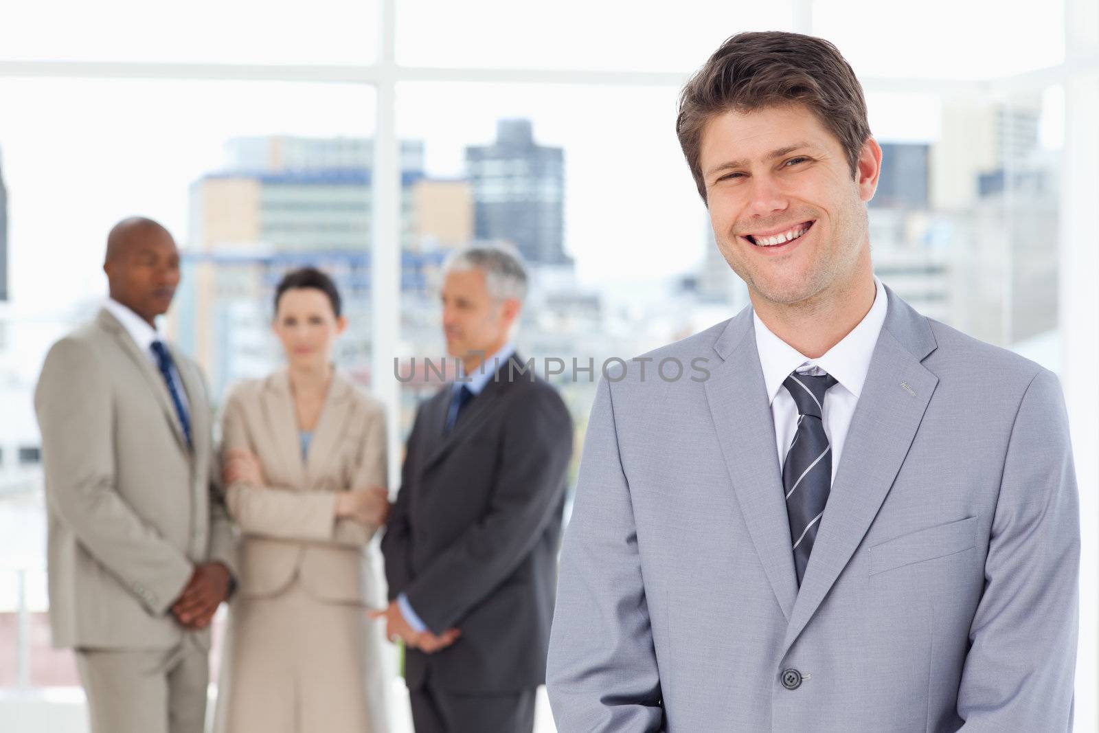 Young smiling manager standing upright with his team behind him by Wavebreakmedia