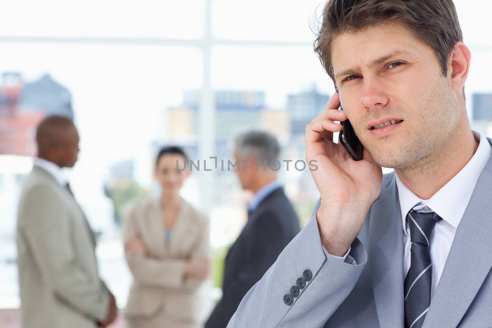 Young executive seriously looking straight ahead while using a mobile phone