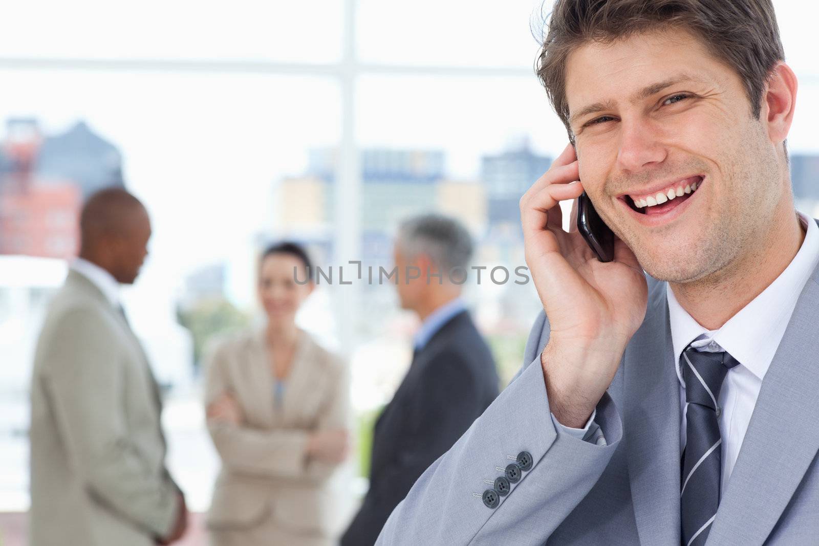 Young manager laughing while using his mobile phone by Wavebreakmedia