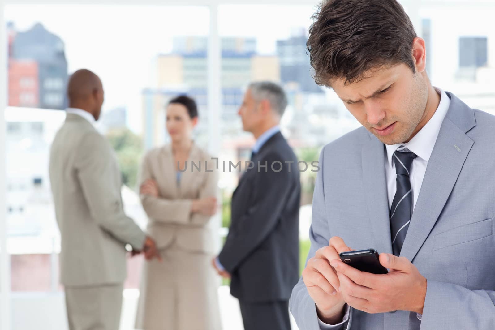 Young serious executive using his mobile phone to send a text