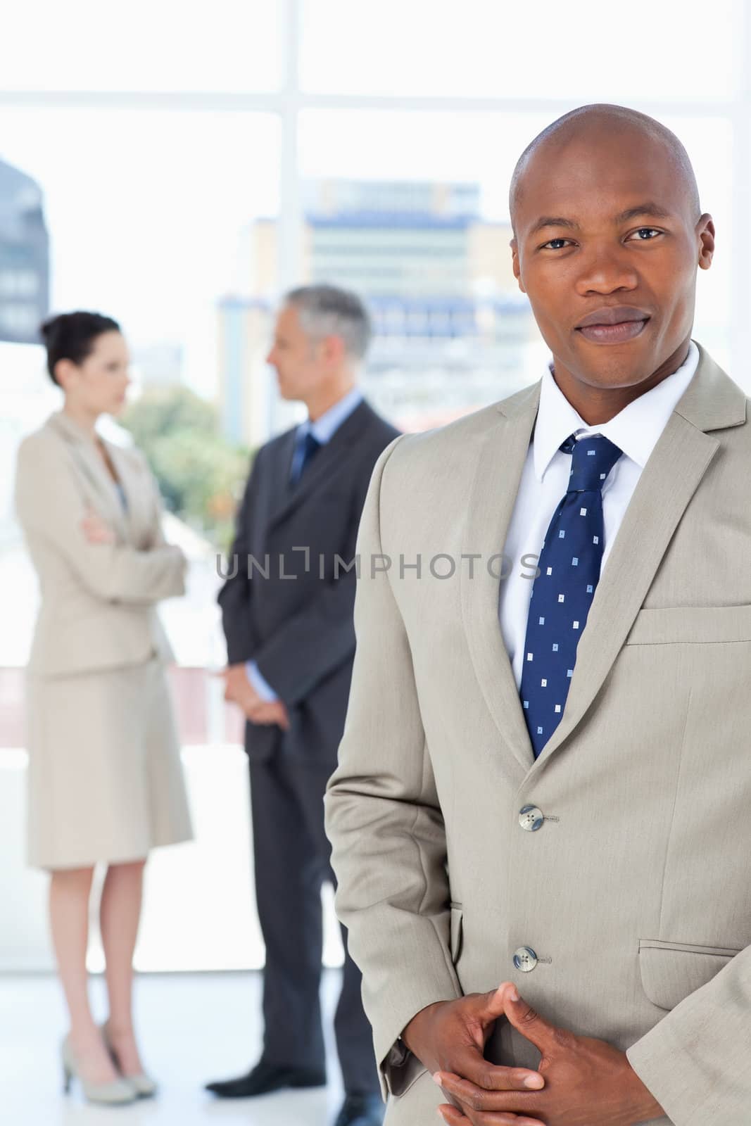 Businessman wearing a suit and crossing his hands with his team  by Wavebreakmedia