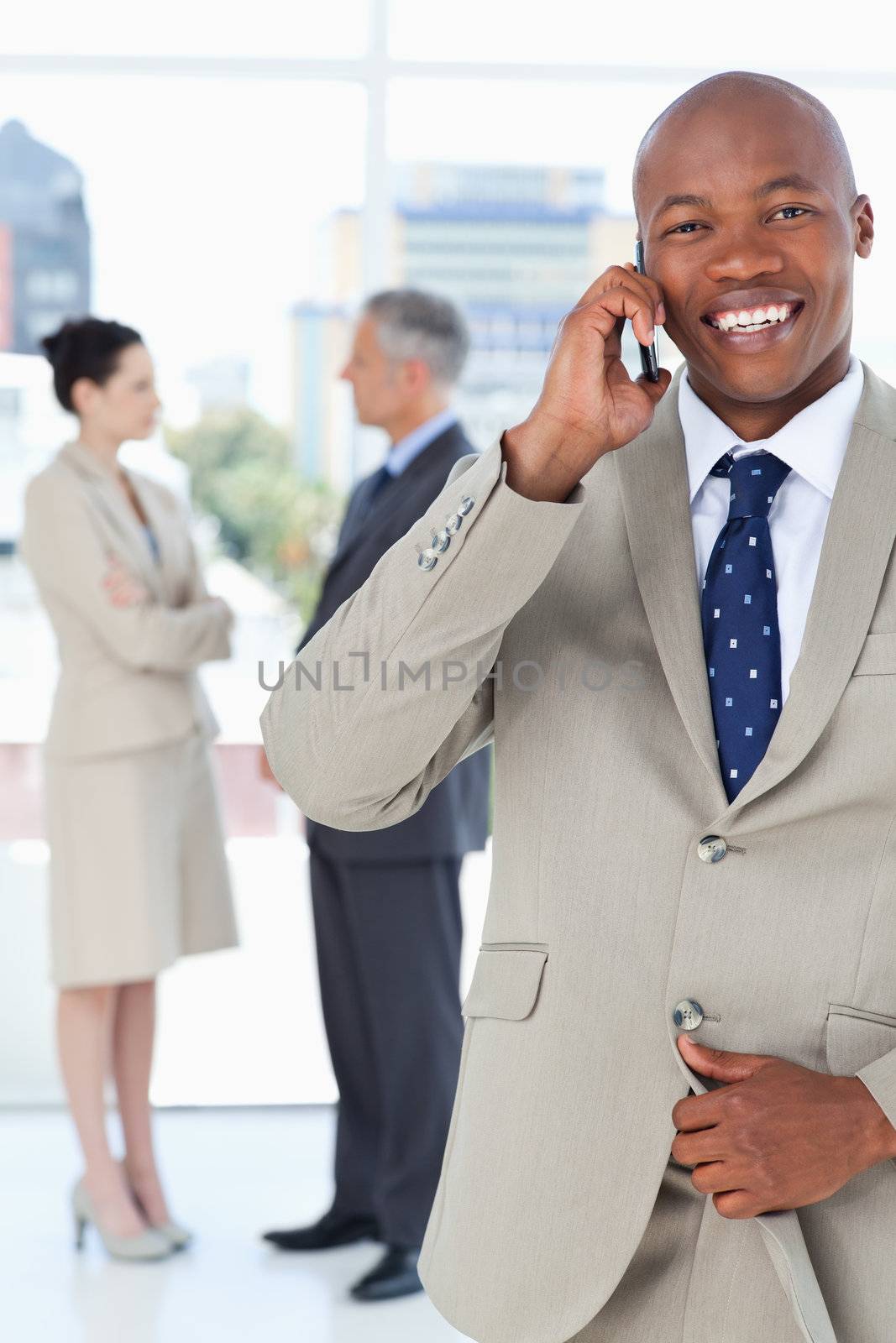 Manager using a mobile phone while unbuttoning his suit jacket by Wavebreakmedia