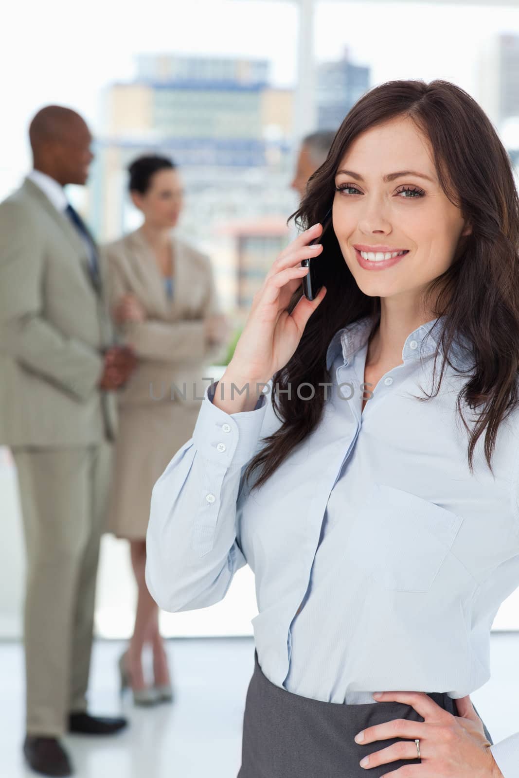 Smiling executive woman talking on the mobile phone with one hand on her hip