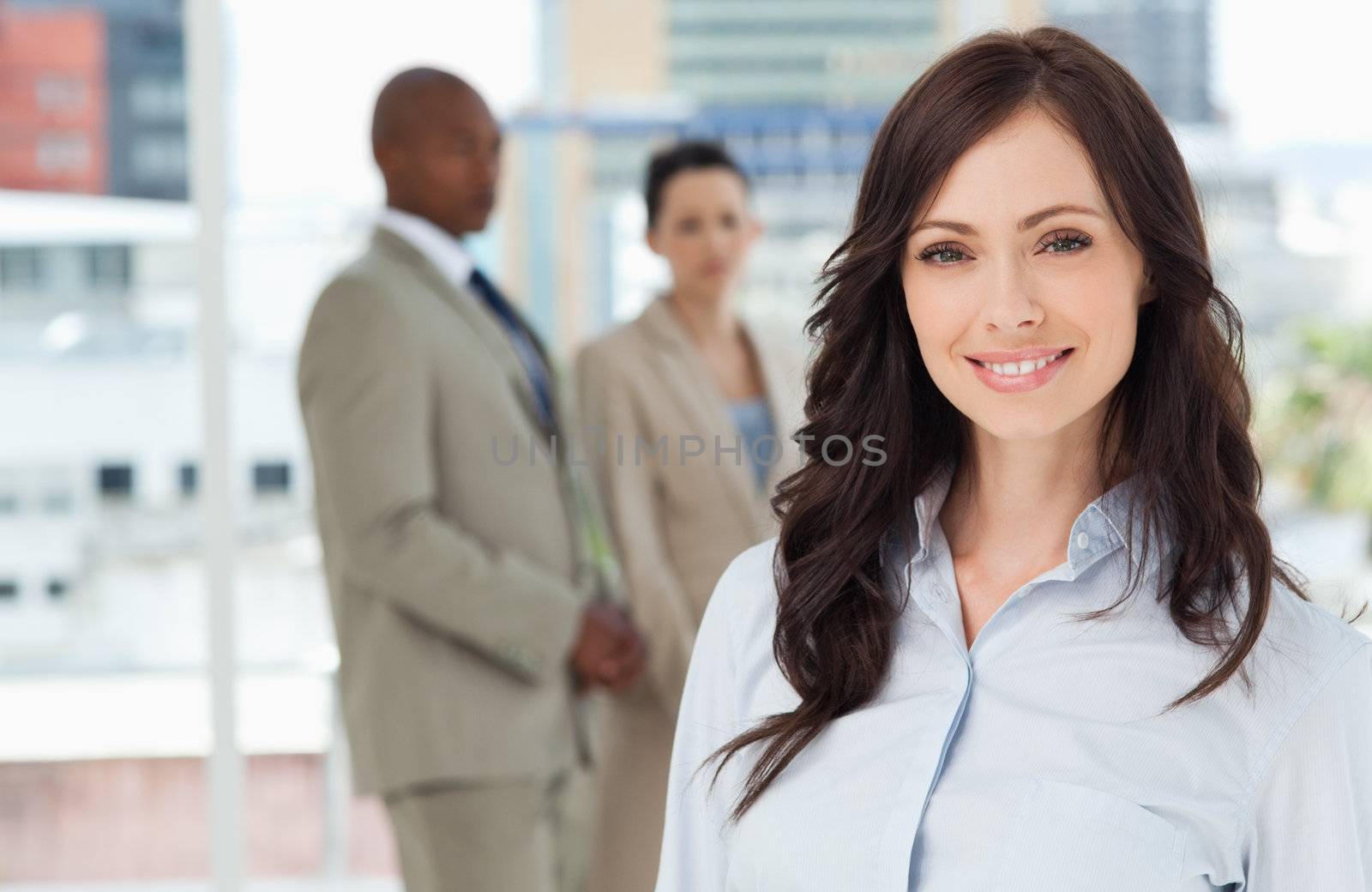 Young smiling executive standing in front of her business team