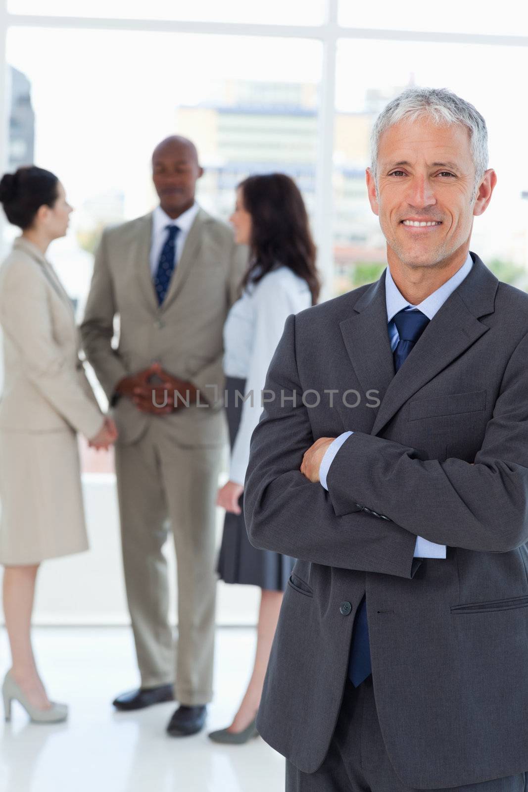 Mature smiling manager crossing his arms in front of his business team