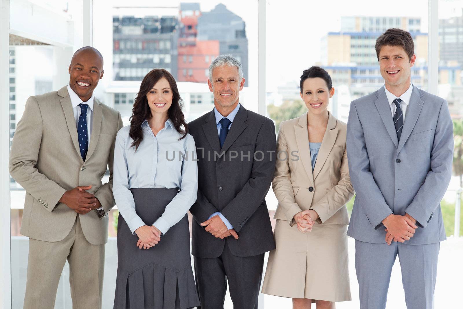 Business team smiling and standing upright side by side with their hands crossed