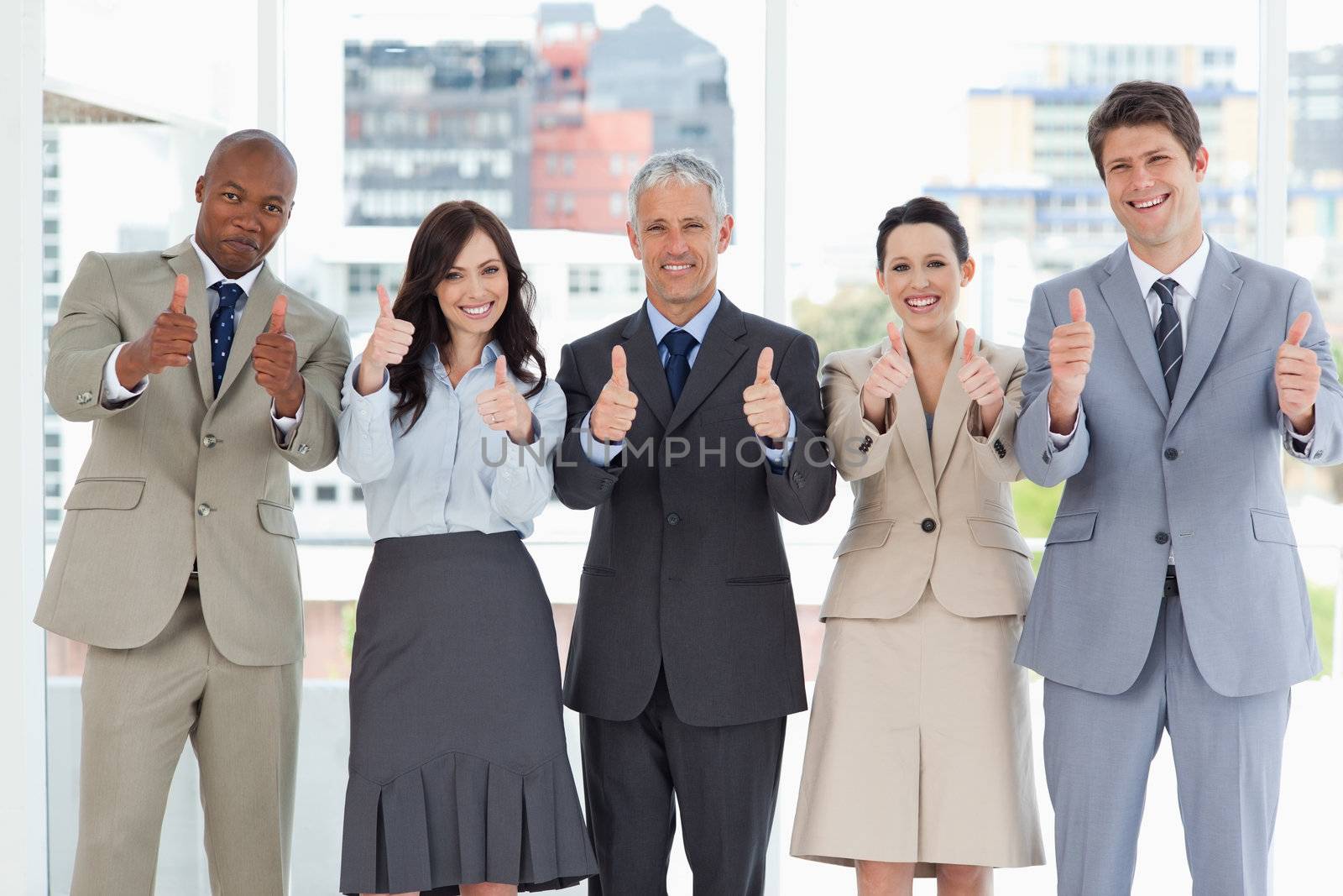 Business team putting their thumbs up to show a success