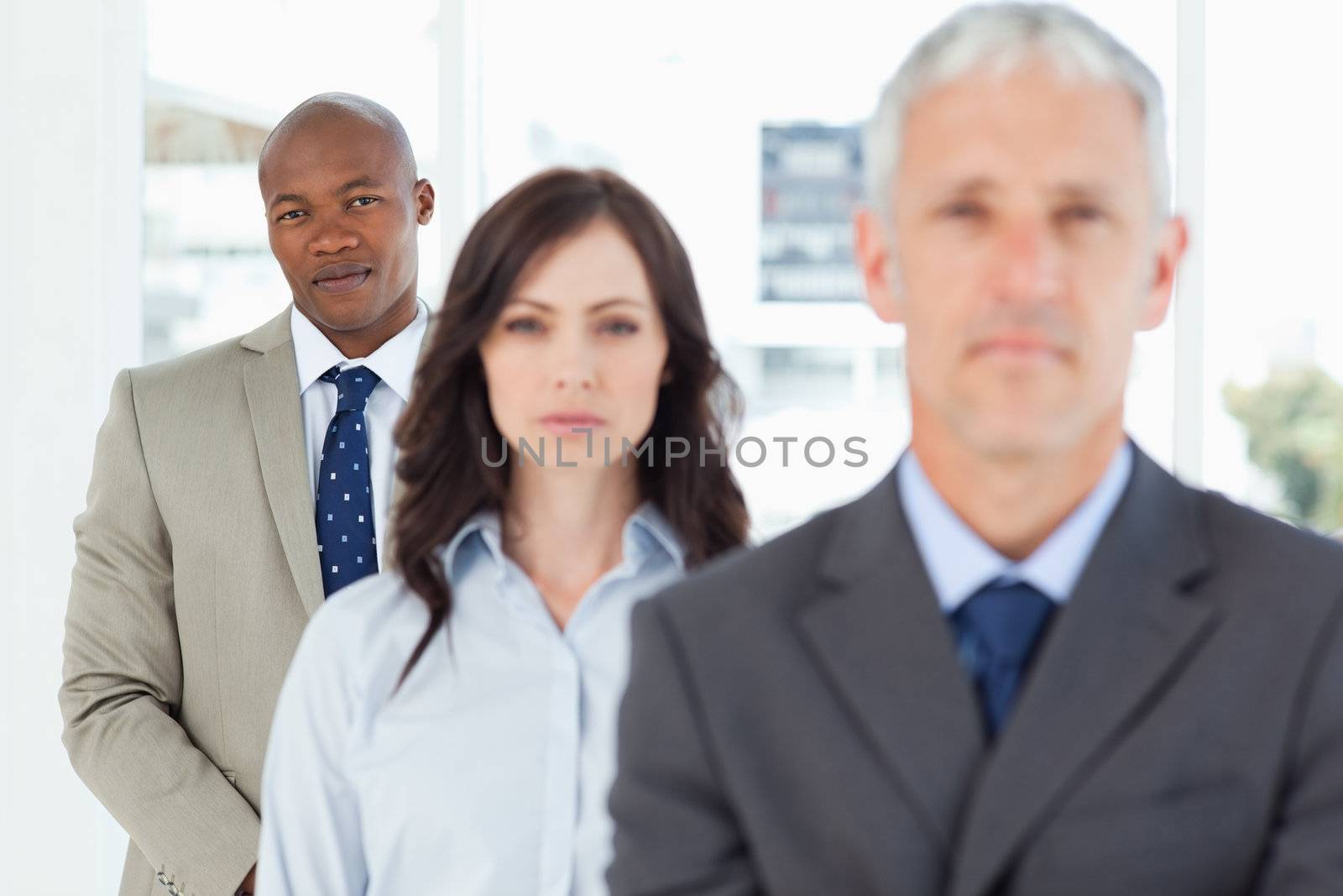 Young businessman following two serious members of his team