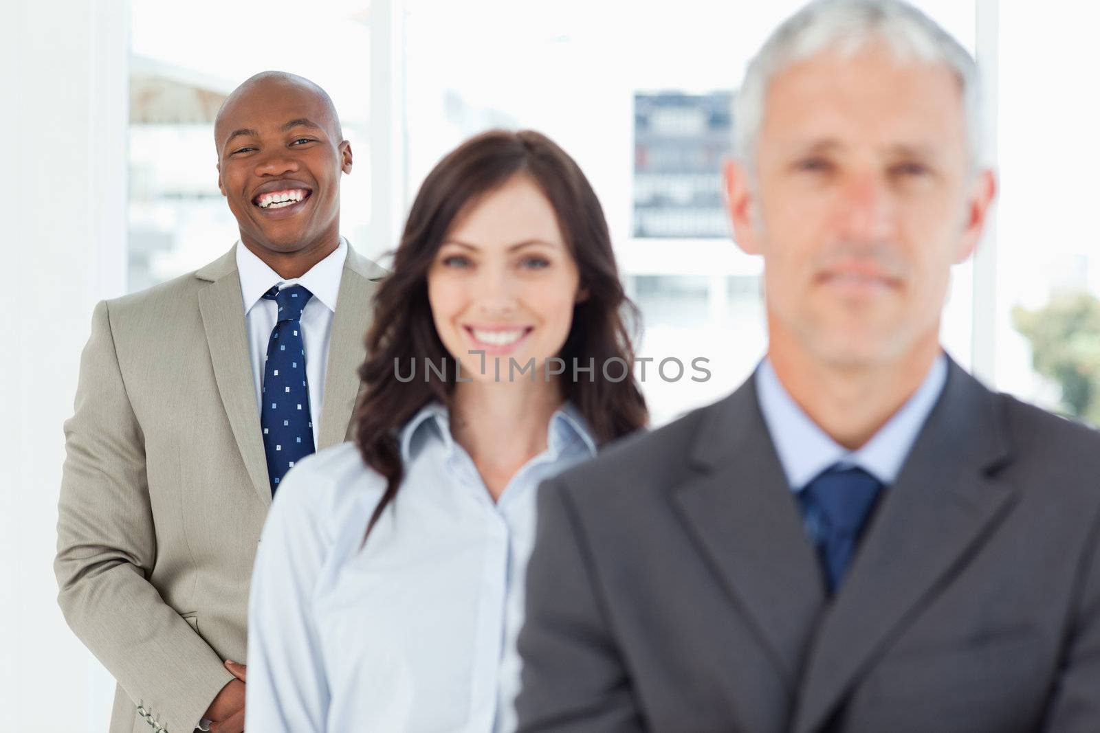 Young smiling employee standing upright and following his team by Wavebreakmedia
