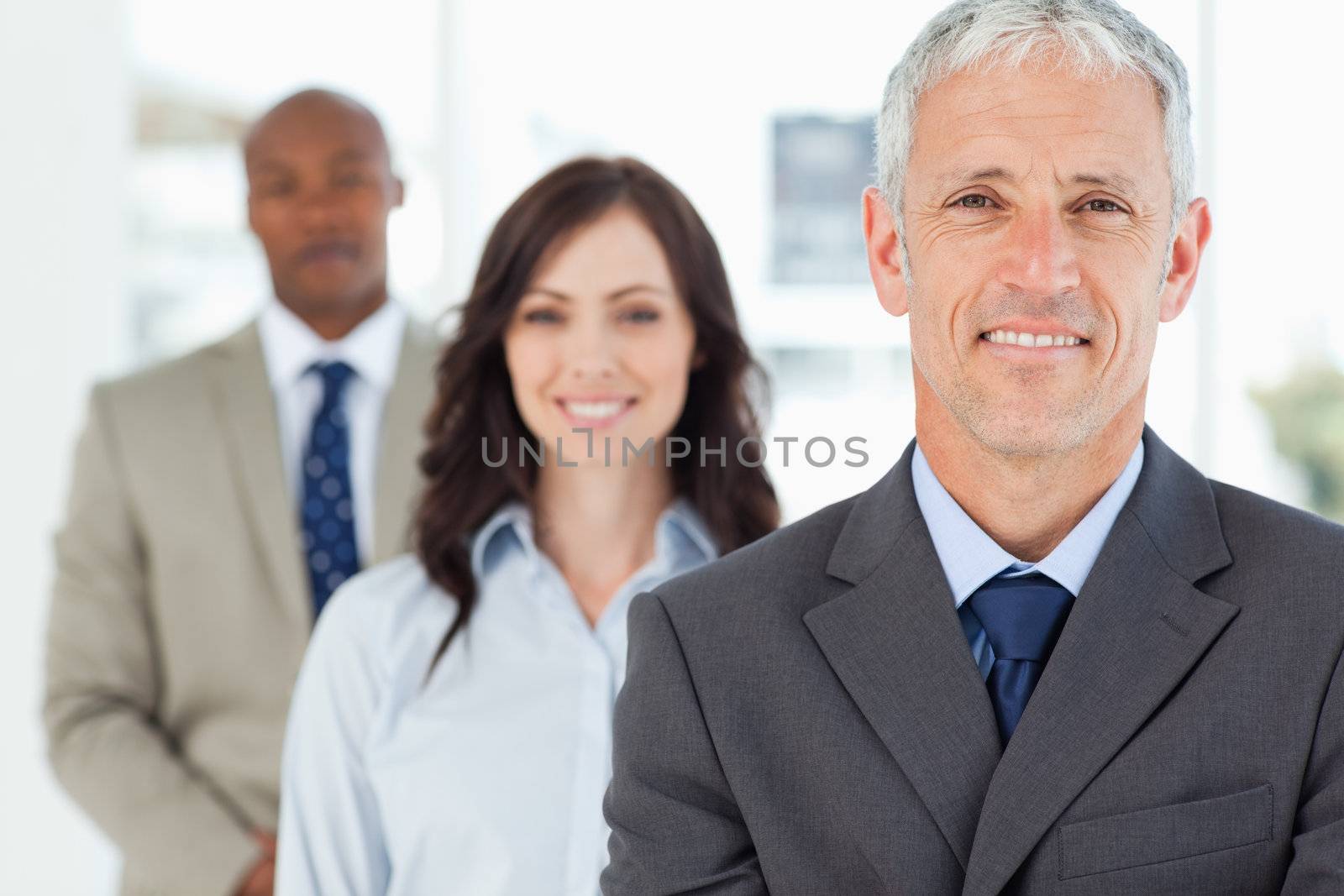 Smiling mature manager with his team following him