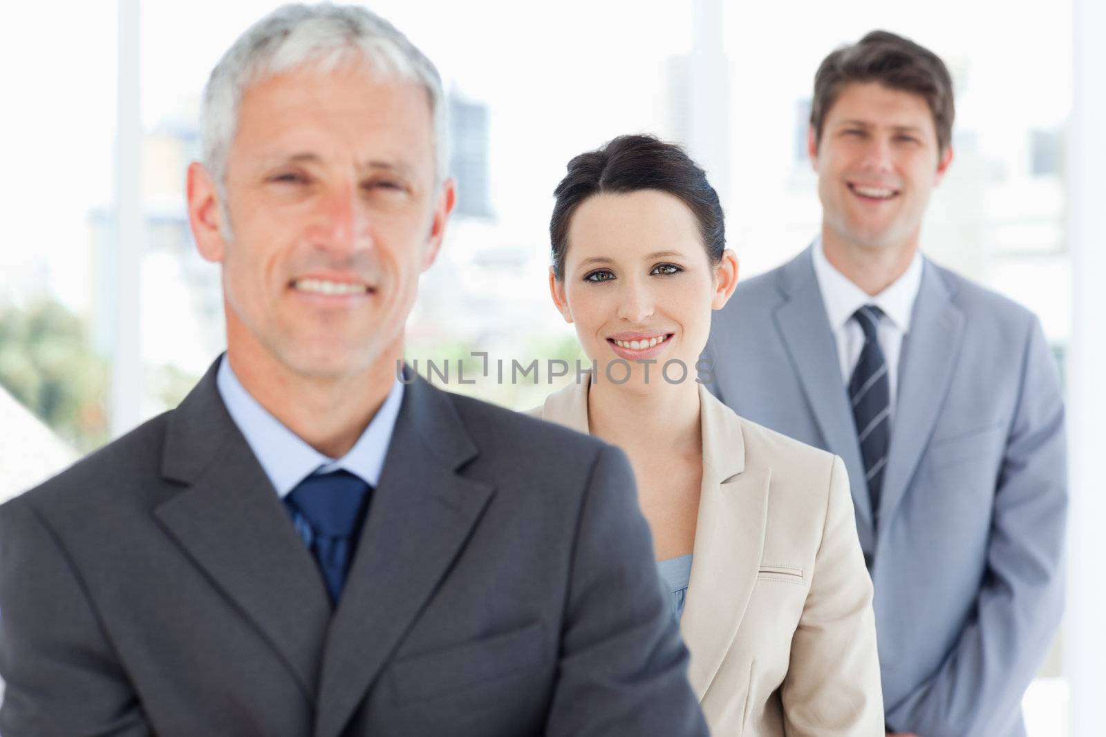 Young smiling businesswoman wearing a formal suit between two executives