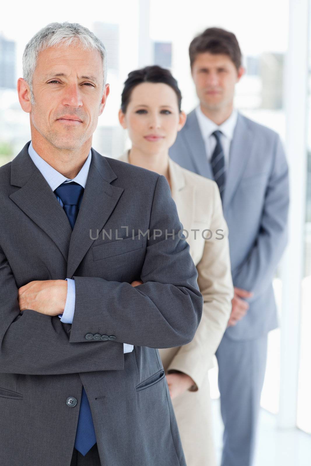 Serious manager crossing his arms in front of his business team by Wavebreakmedia