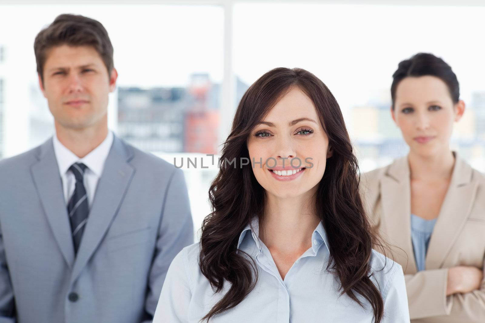 Young smiling woman standing in front of two co-workers by Wavebreakmedia