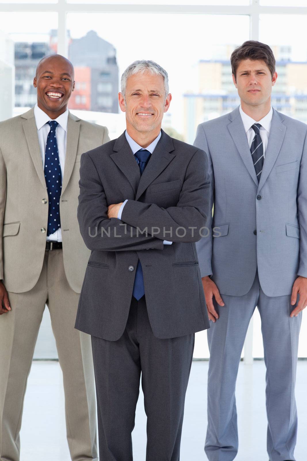 Smiling director standing in front of a relaxed executive and a serious employee