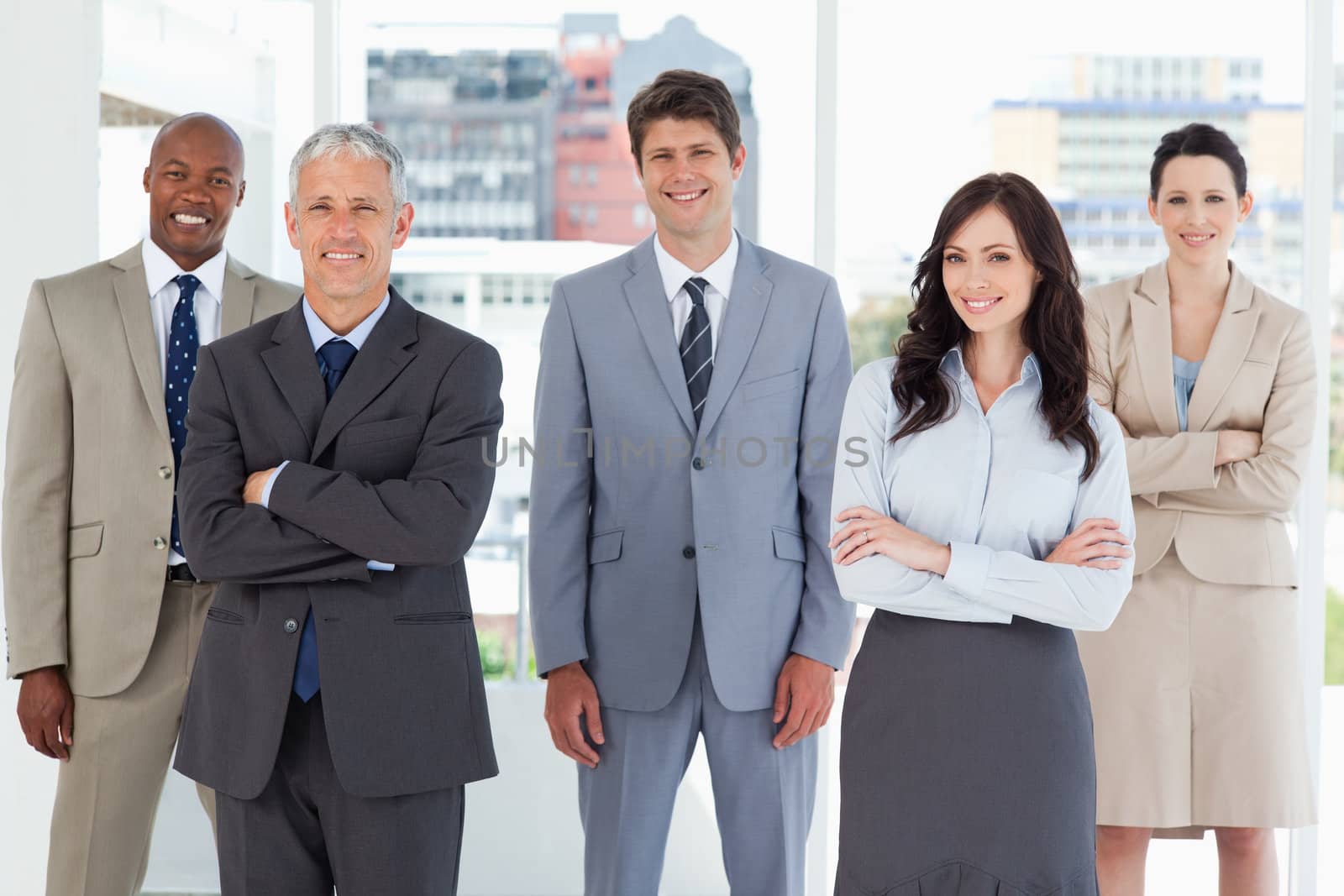 Young smiling executive standing in the middle of the room among his colleagues