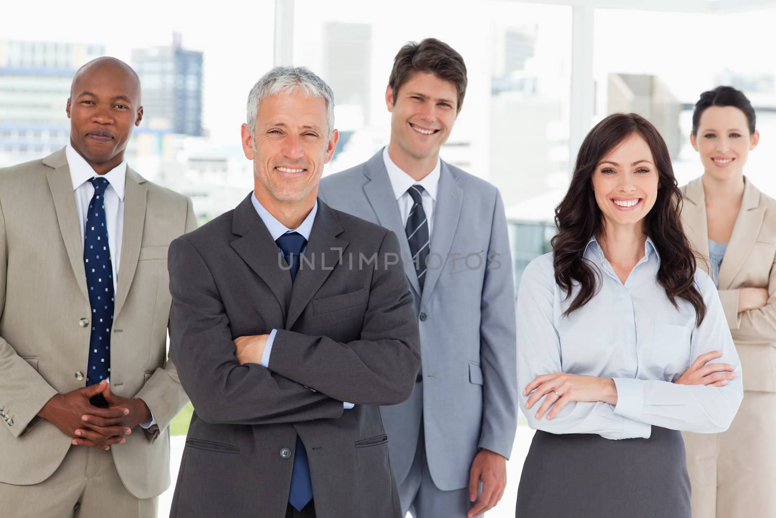 Smiling business team standing in front of a bright window by Wavebreakmedia