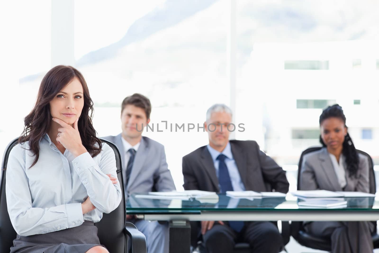 Confident businesswoman sitting with her hand on her chin while  by Wavebreakmedia