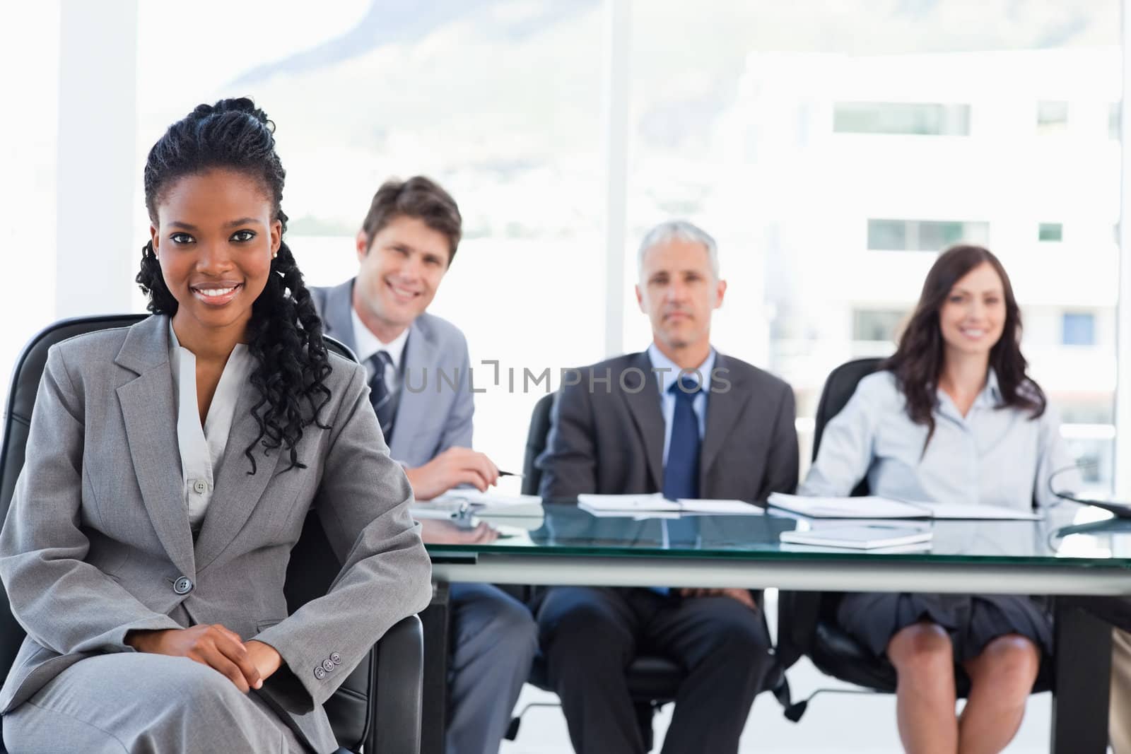 Young executive woman smiling while sitting with her legs crossed and her hands on her leg