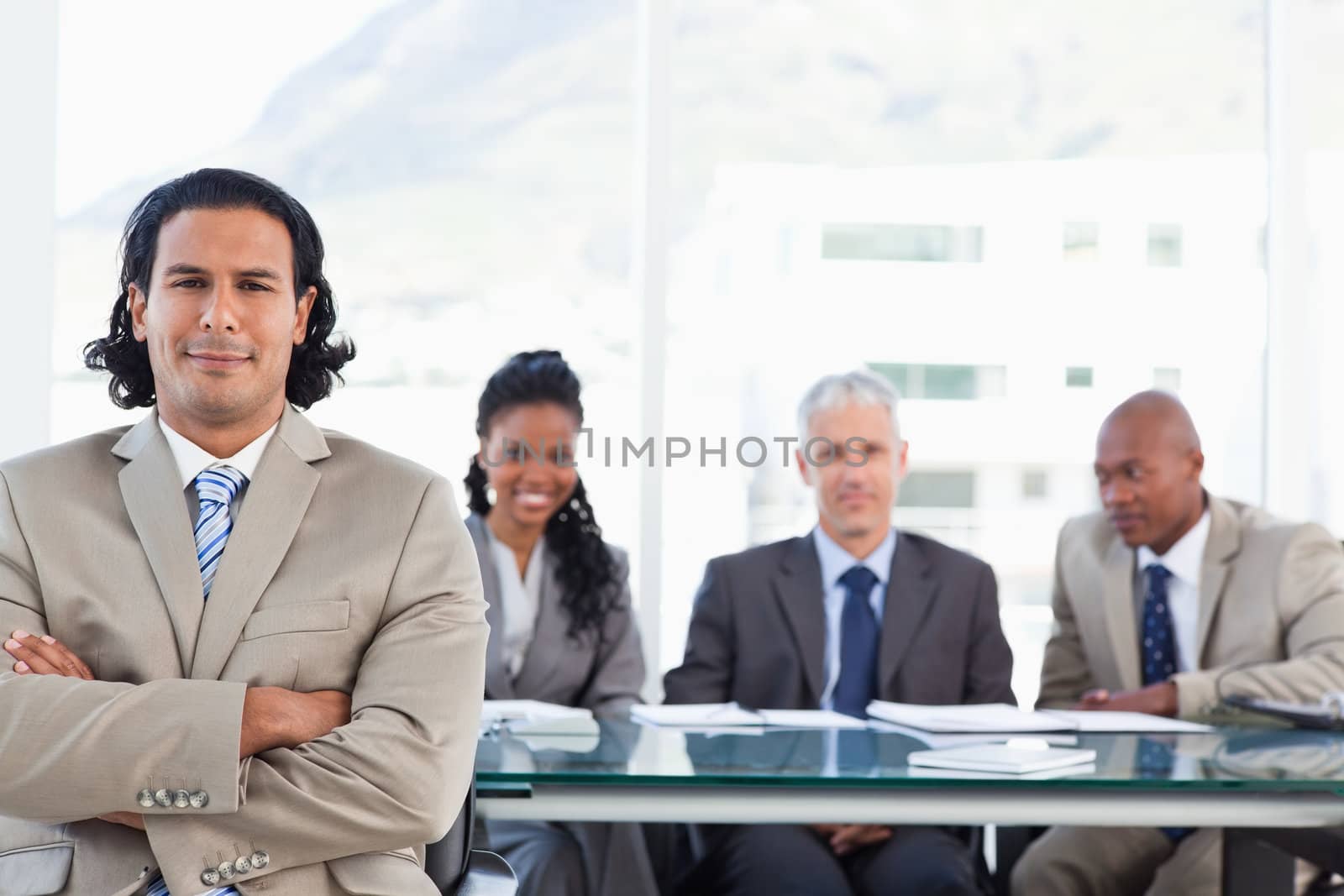 Stern businessman crossing his arms while his team in the back i by Wavebreakmedia