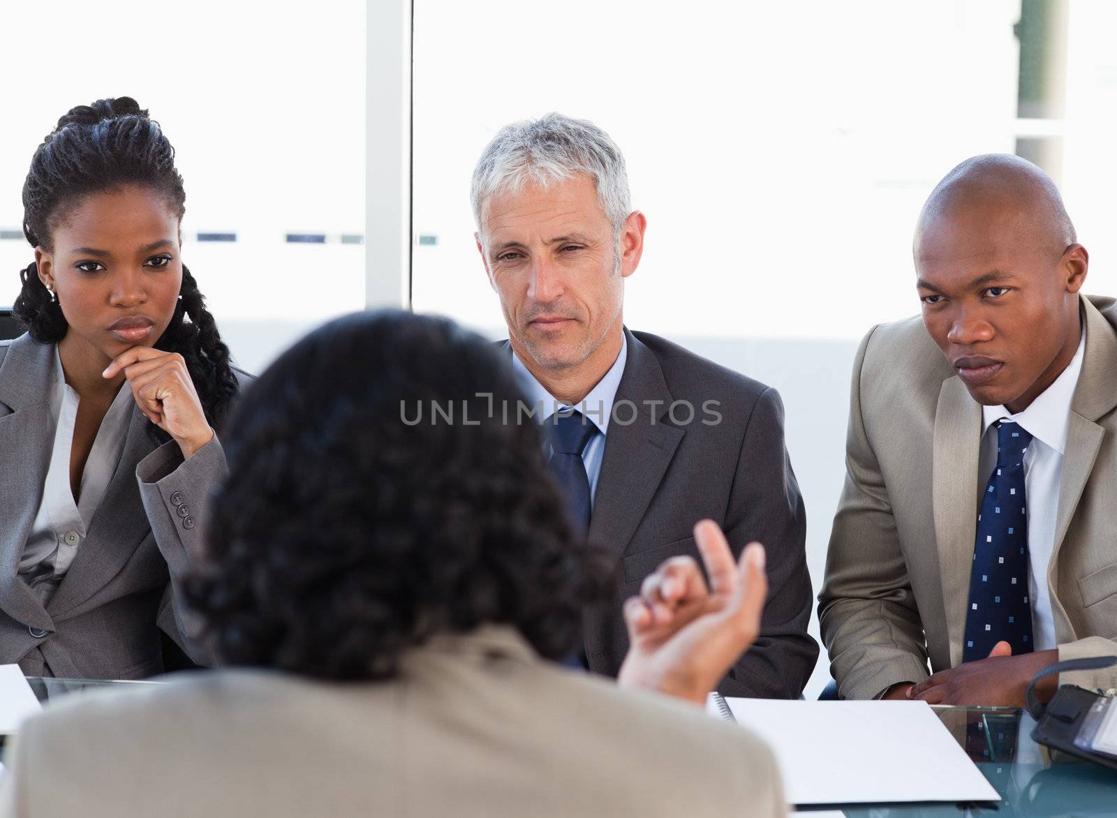 Business people attentively listening to a serious speaker in a meeting