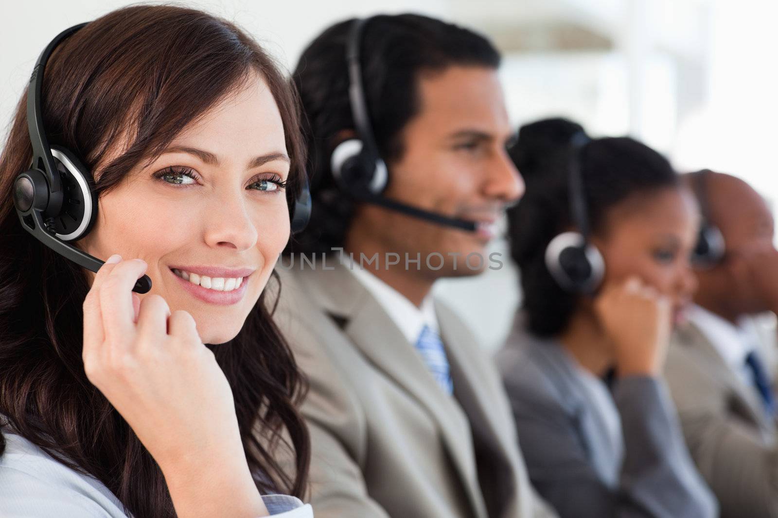 Smiling employee working with a headset while looking at the cam by Wavebreakmedia