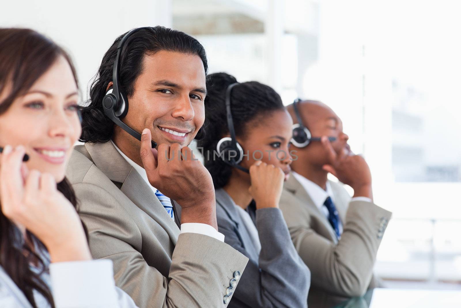 Young smiling call centre employee working among his team