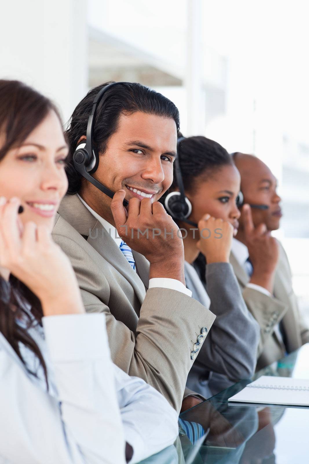 Young smiling call centre worker working among his business team by Wavebreakmedia