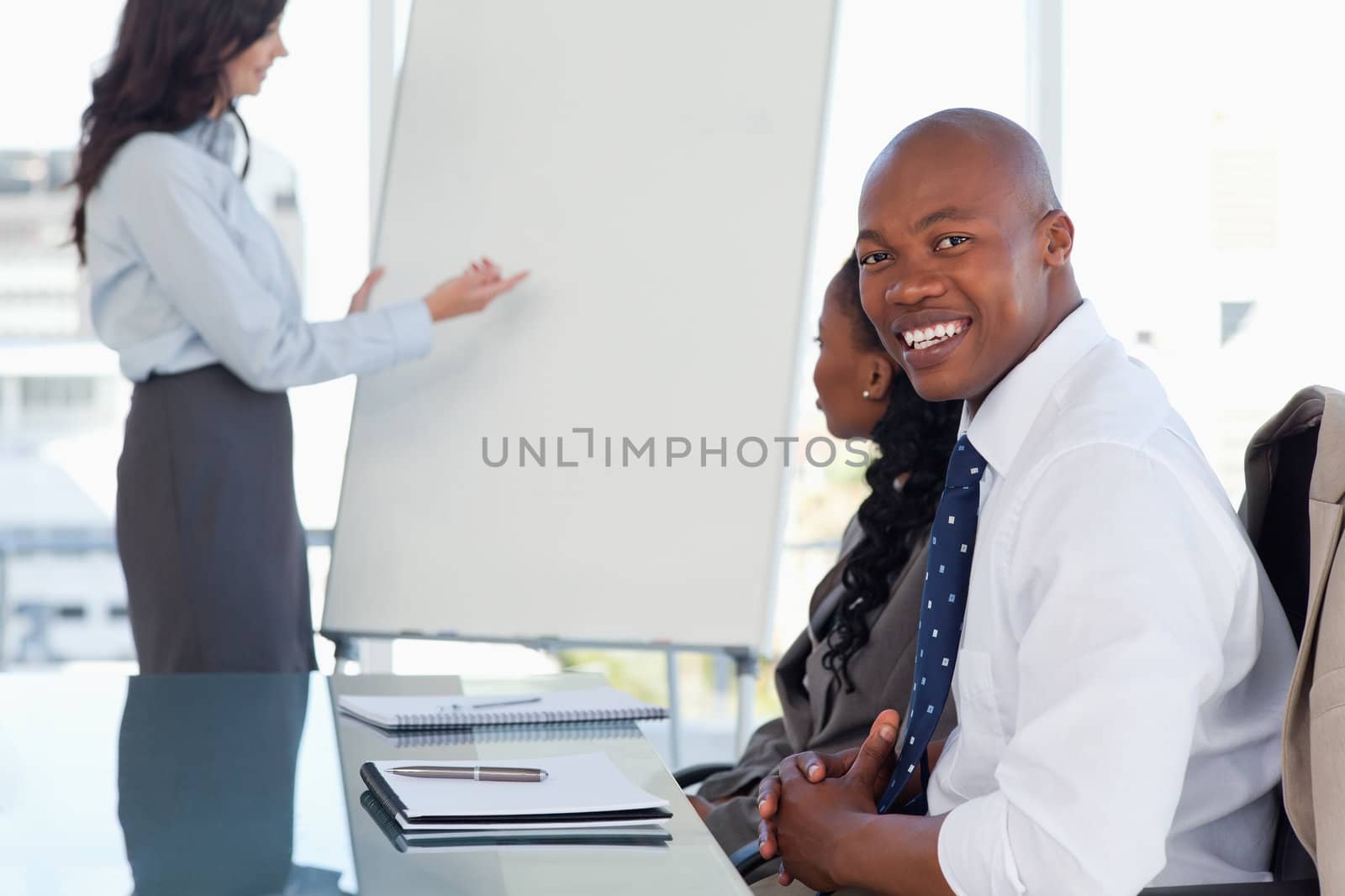 Young smiling executive sitting with his hands crossed and listening to a presentation