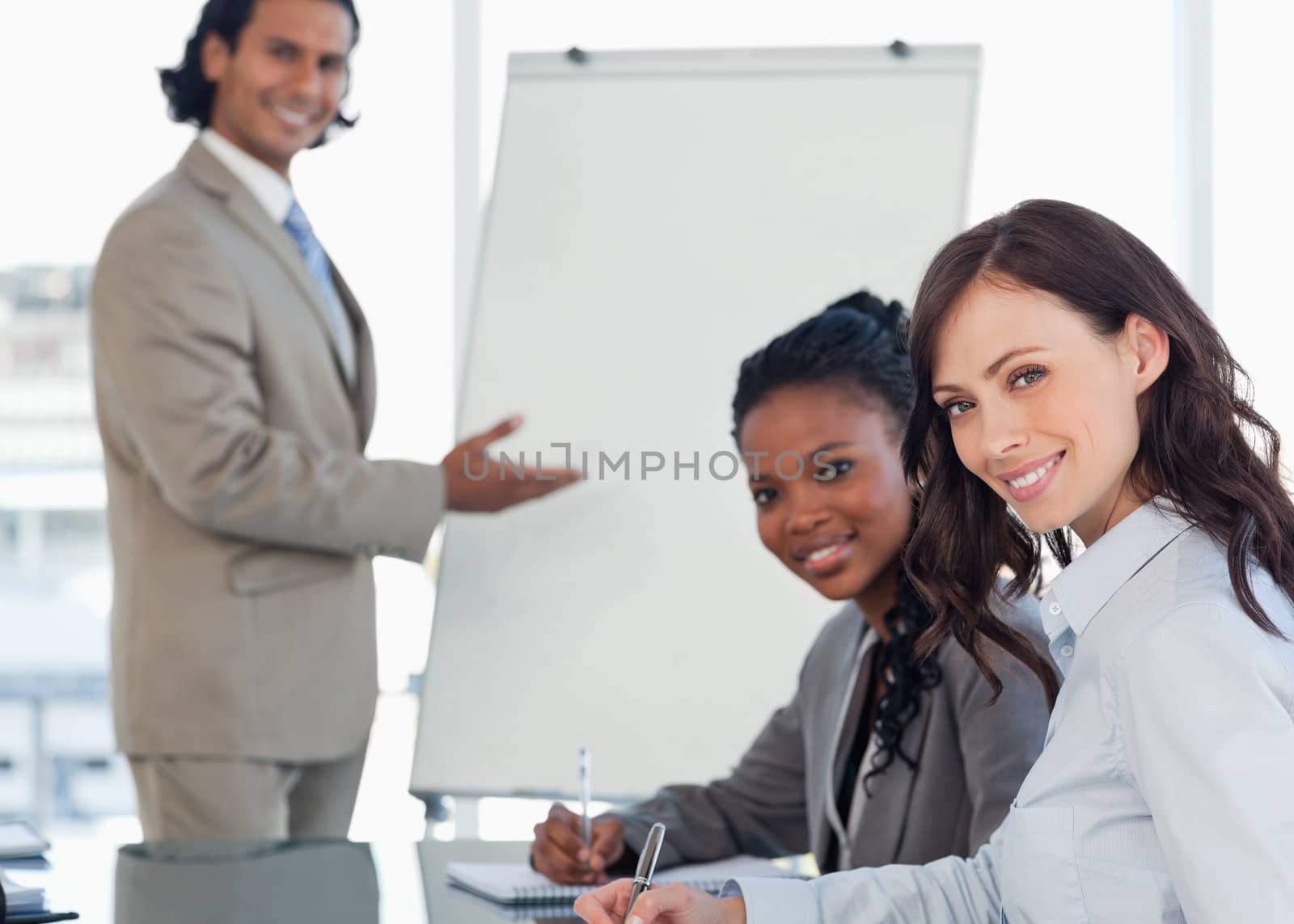 Young smiling executives sitting at the desk with a co-worker behind them