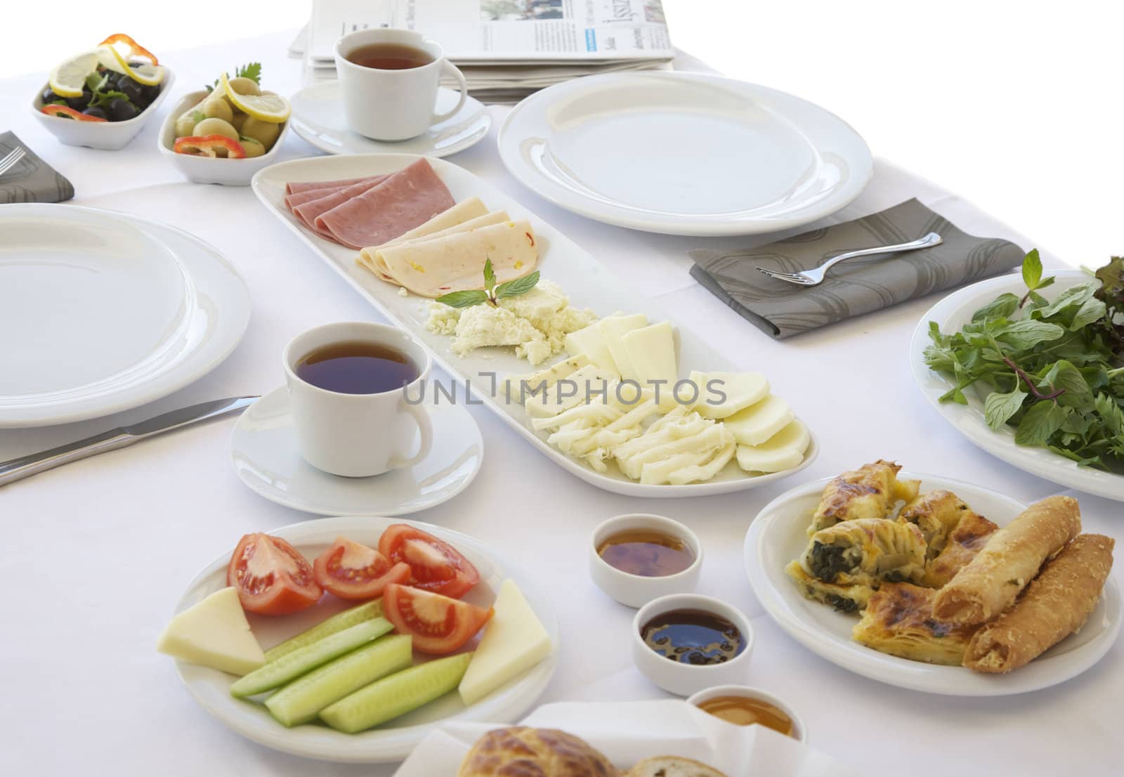 Breakfast table with cheese, tomatoes, olives, cucumber and pastries