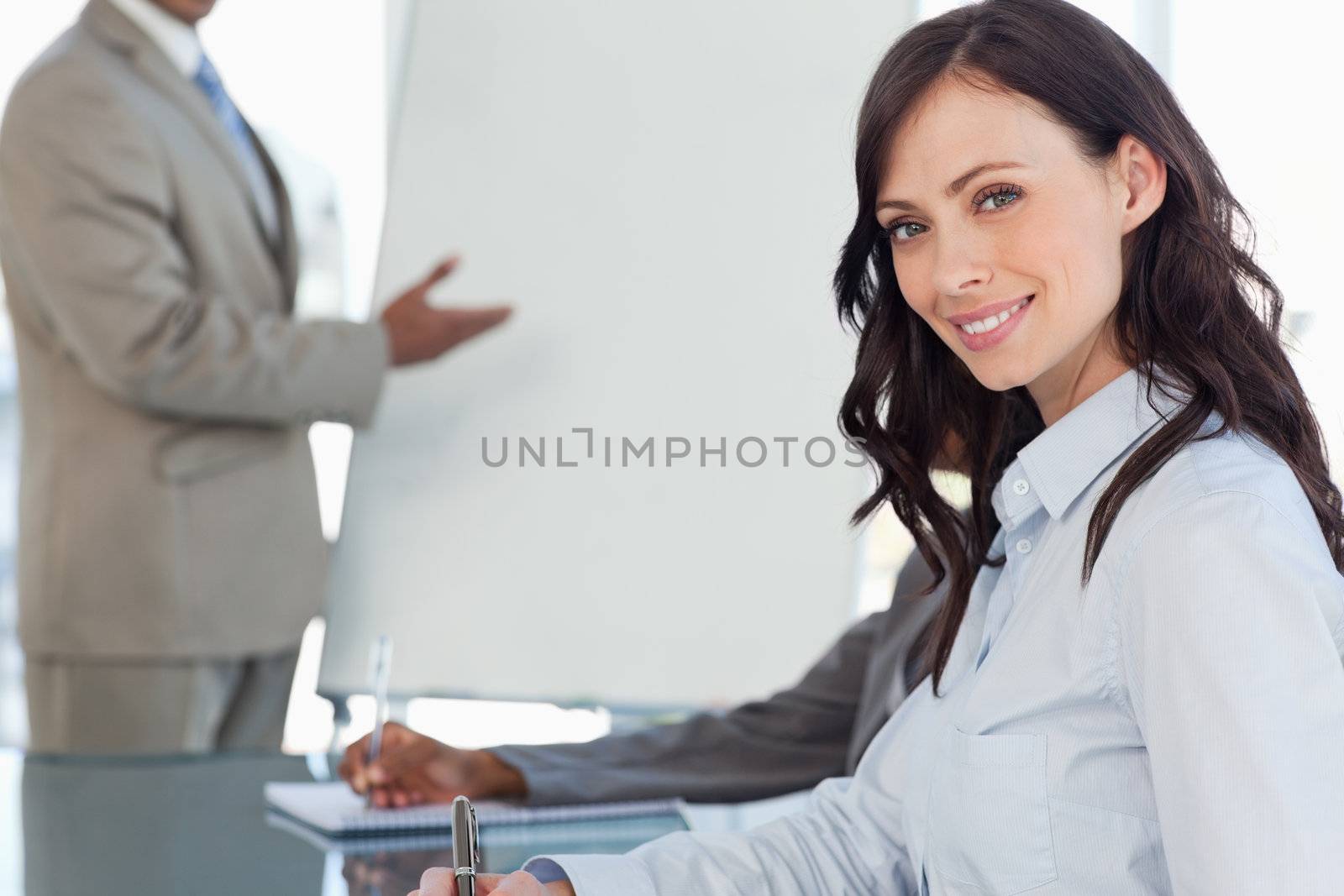 Smiling businesswoman writing in a notebook during a presentation