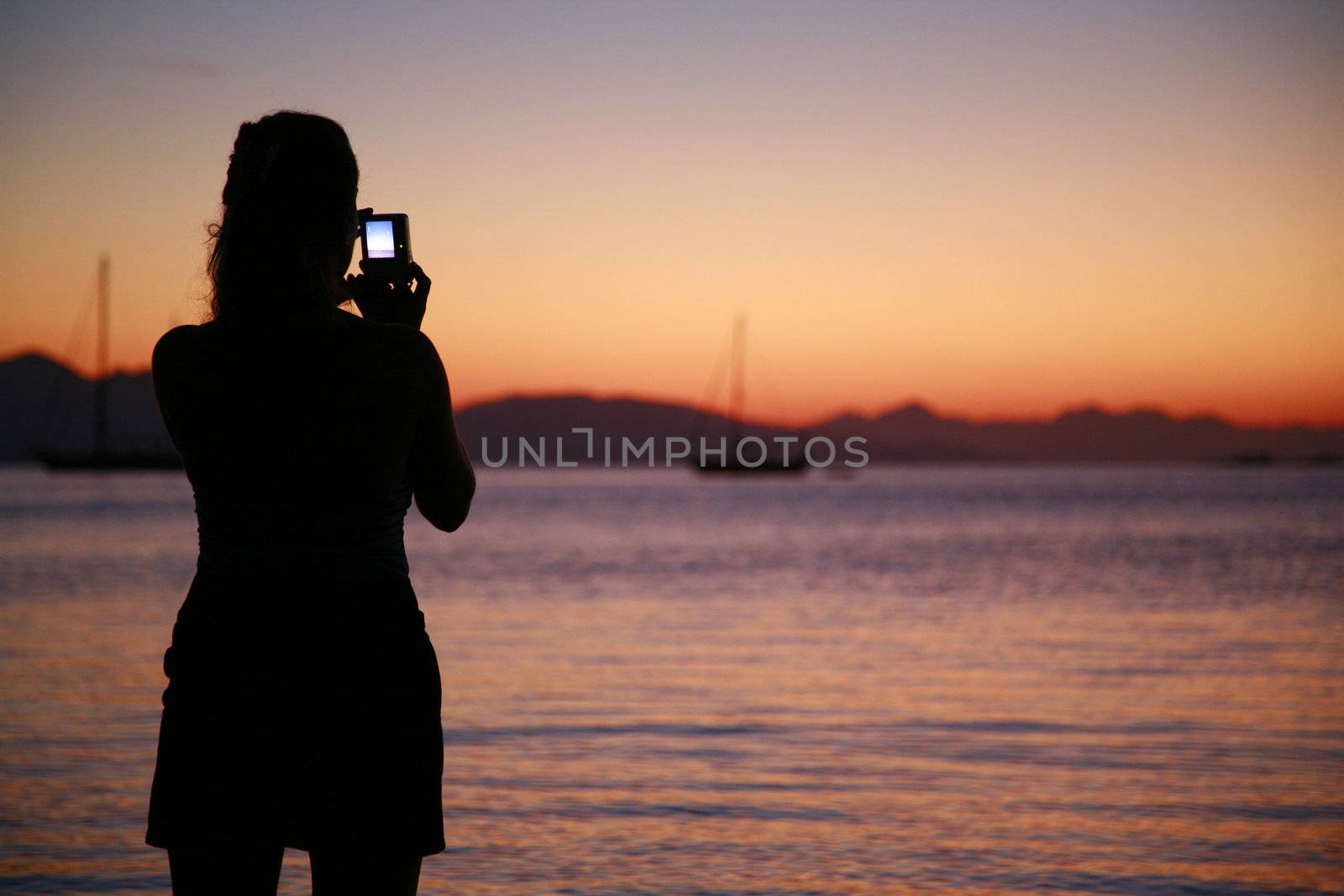 Girl is taking picture of beatiful sunset by necatiturker