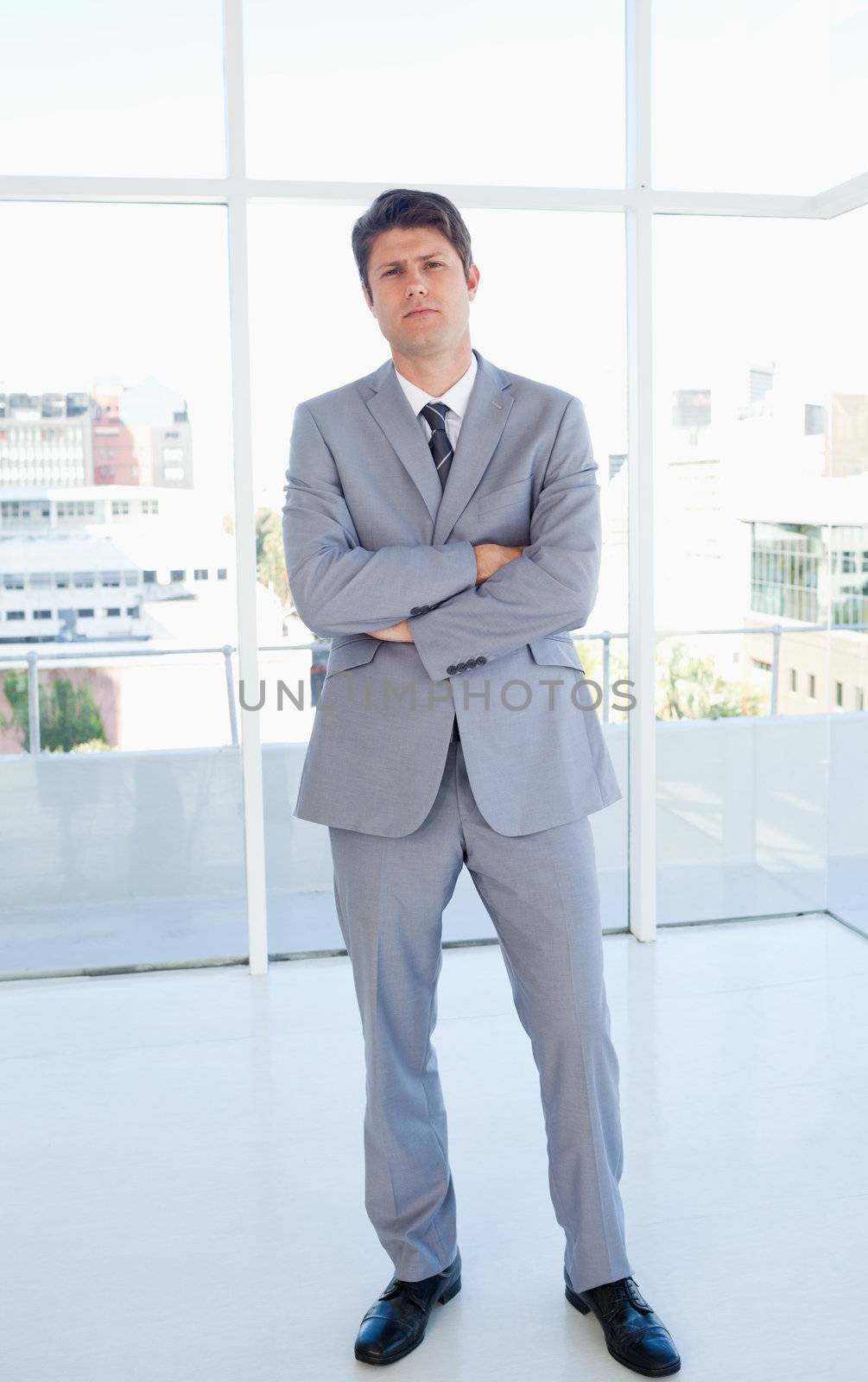 Businessman crossing his arms and standing upright in front of a bright window
